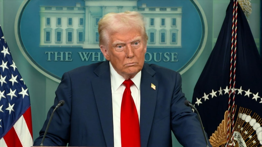 President Donald Trump standing at a podium in the White House briefing room, wide-eyed and seemingly unhappy.