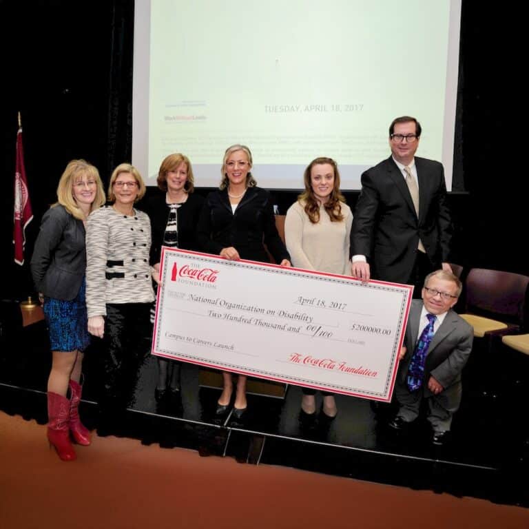 Members of NOD and teen graduates with disabilities holding a large check