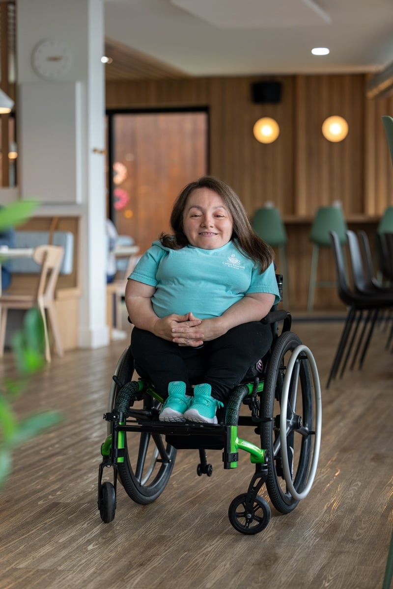 Jessica sitting in a wheelchair with her hands on her lap, smiling