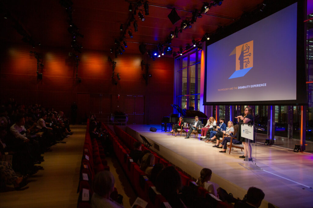 A faraway photo of a panel of speakers together in a room