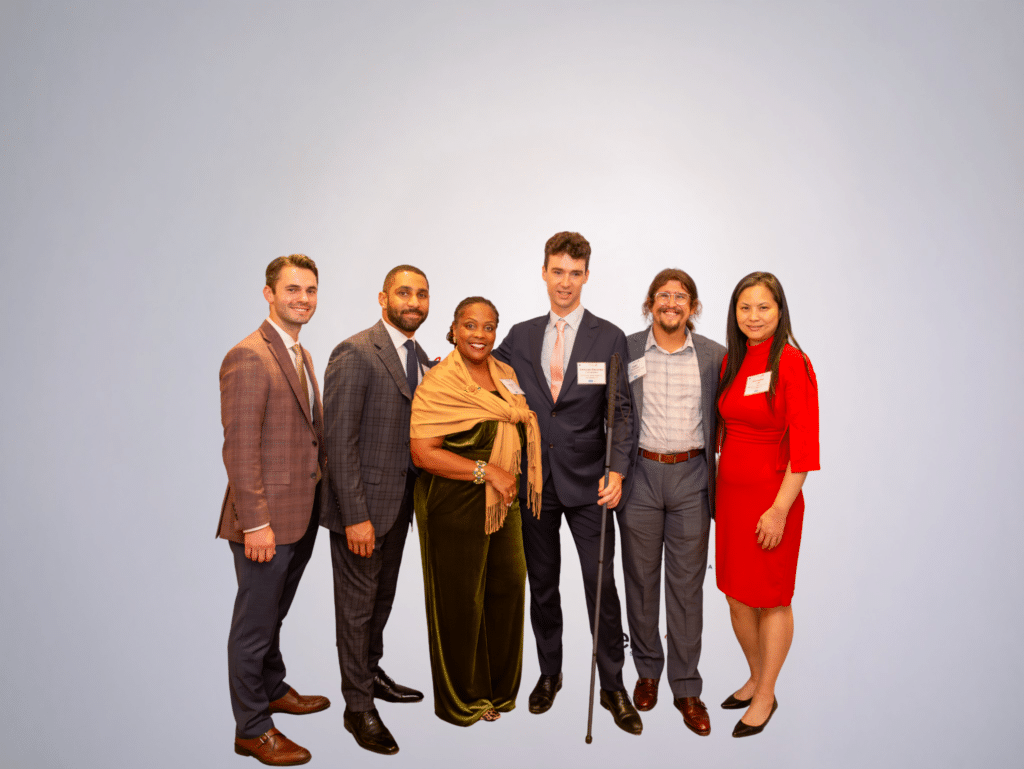 A group of six people standing together, dressed up and smiling