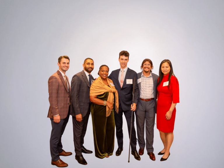 A group of six people standing together, dressed up and smiling