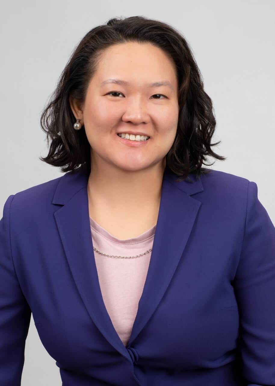 Headshot of an Asian American woman wearing a purple blazer smiling at the camera