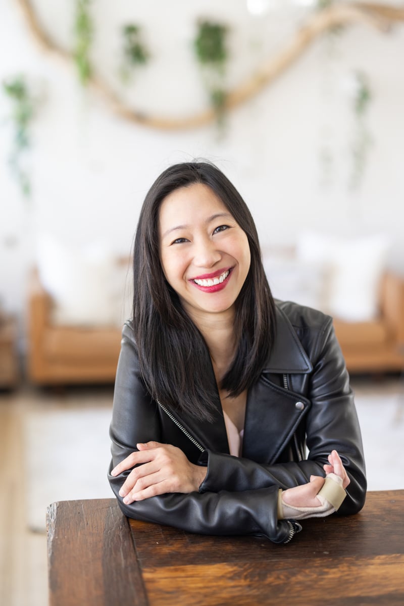 Tiffany Yu smiling into the camera, with her arms crossed and resting on the table