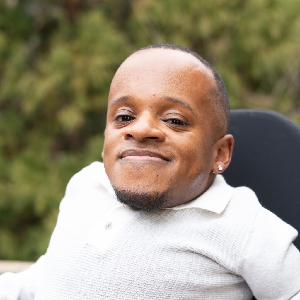 Headshot of Winston, wearing a white shirt and smiling confidently at the camera