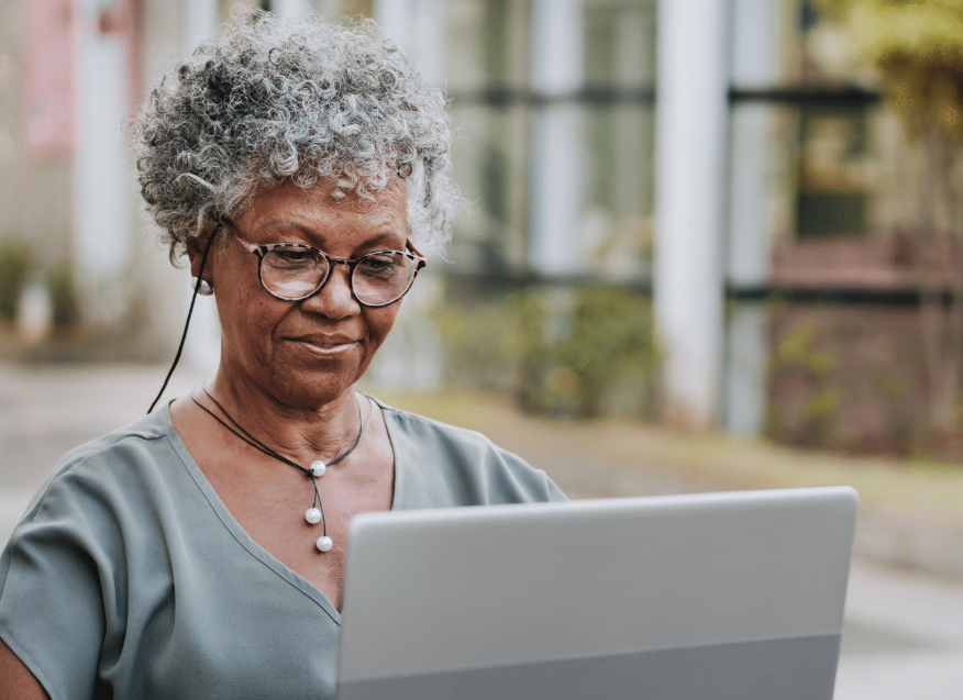 An elderly woman looking at a computer.