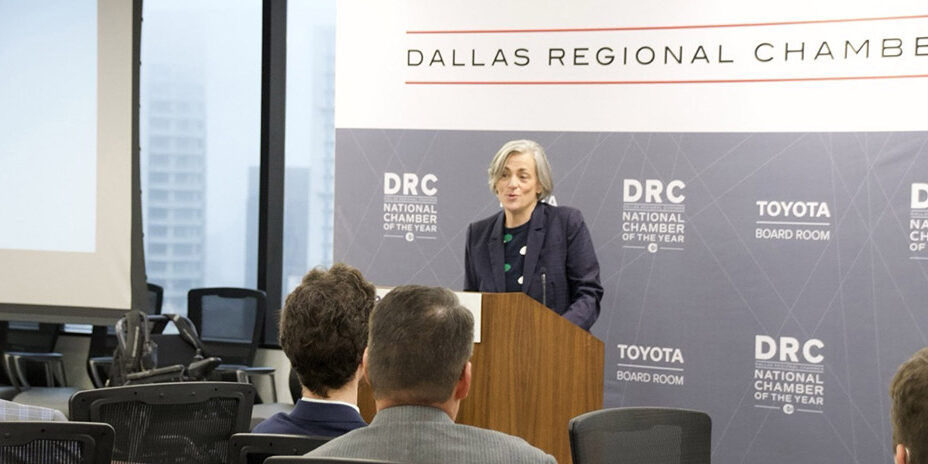 Beth Sirull speaking at a podium in front of a DRC-branded step and repeat