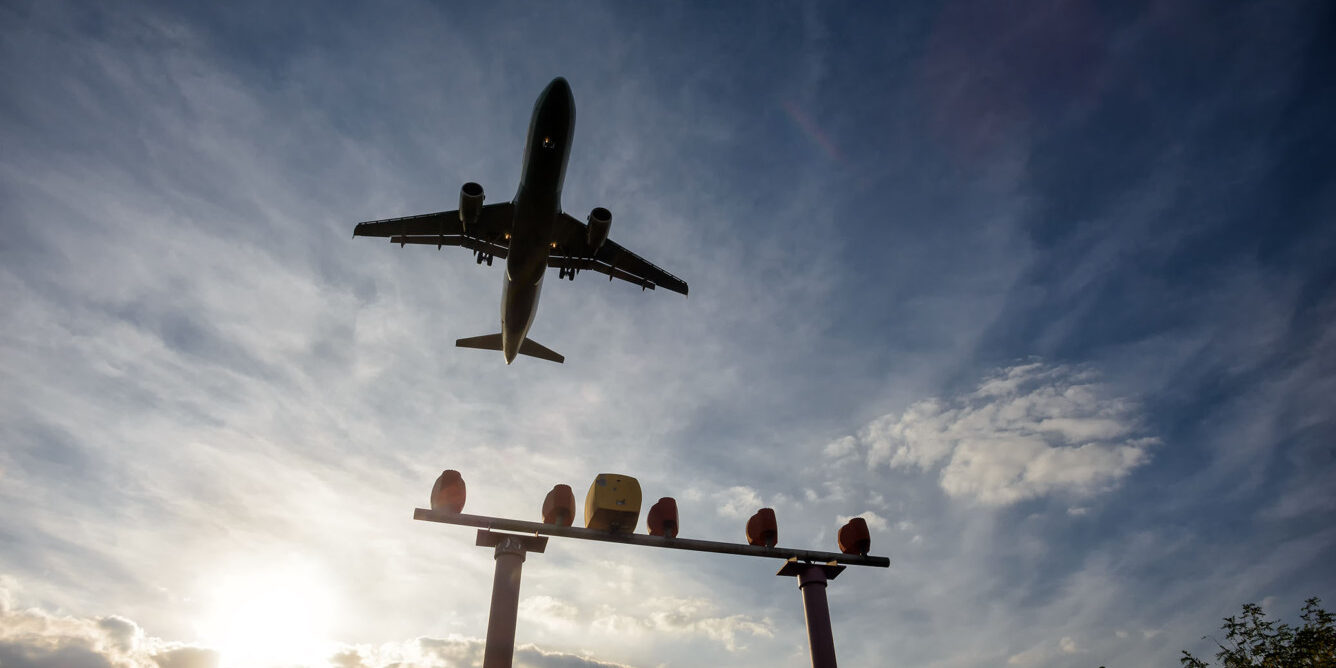 View looking up at the sky with the silhouette of a plane flying above.