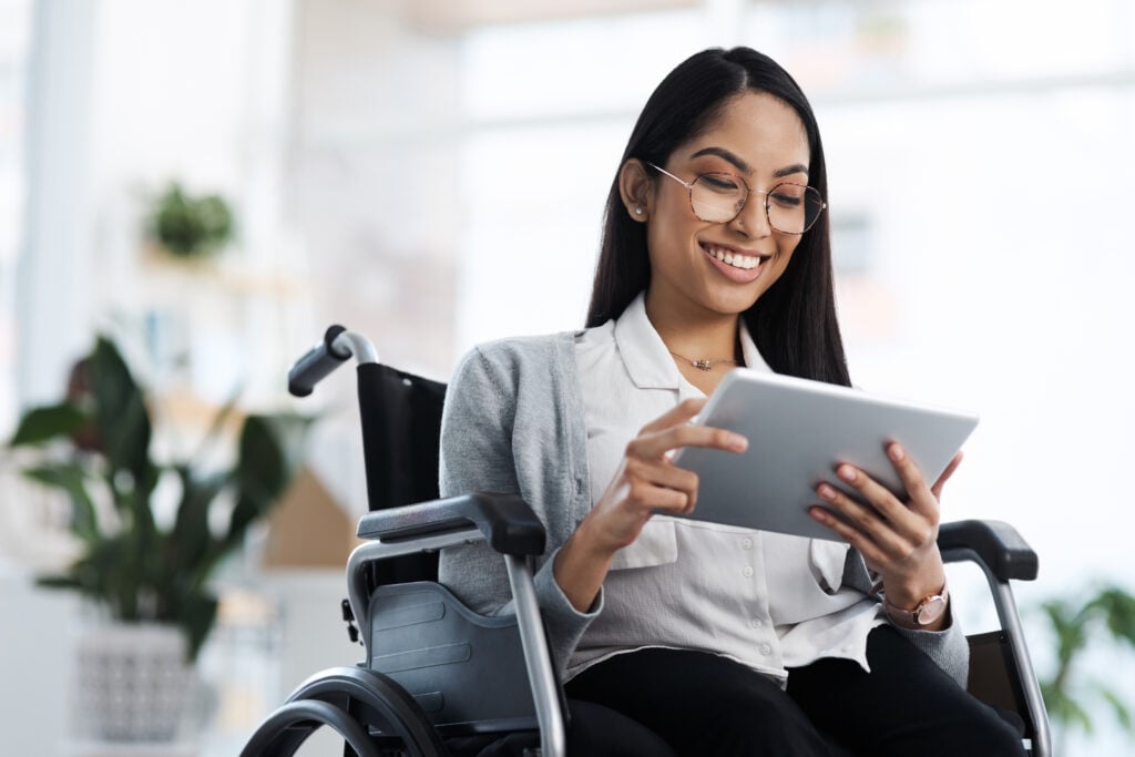 Cropped Shot Of A Young Businesswoman In A Wheelchair Using Her Tablet In The Office