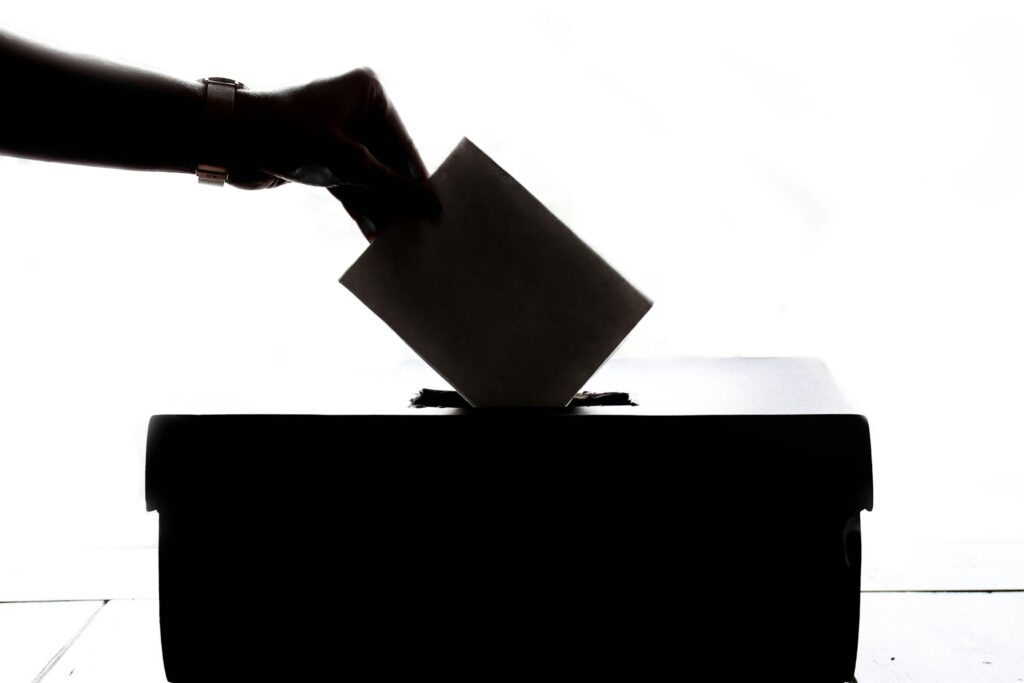 A hand putting a paper ballot into a box