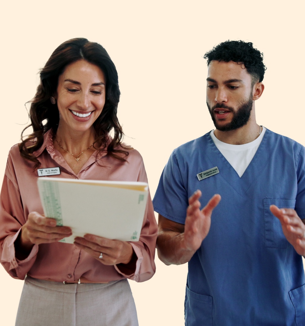 Medical professionals walking and speaking together. They are looking at a medical chart packet of papers. the woman is similing